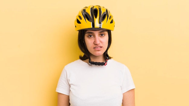 Jovem mulher hispânica se sentindo confuso e confuso conceito de capacete de bicicleta