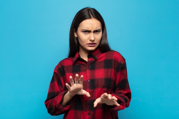 Foto jovem mulher hispânica se sentindo enojada e com náuseas, se afastando de algo desagradável, fedorento ou fedorento, dizendo eca