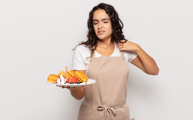 Jovem mulher hispânica se sentindo estressada, ansiosa, cansada e frustrada, puxando a gola da camisa, parecendo frustrada com o problema