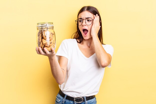 Jovem mulher hispânica se sentindo feliz, animada e surpresa. conceito de garrafa de biscoitos