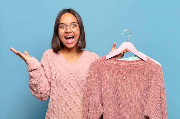 Jovem mulher hispânica se sentindo feliz, animada, surpresa ou chocada, sorrindo e atônita com algo inacreditável