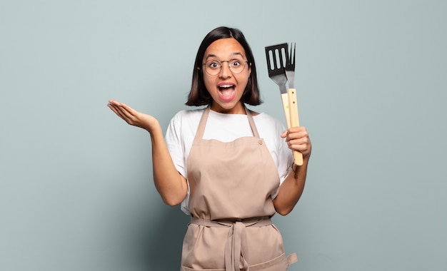 Jovem mulher hispânica se sentindo feliz, animada, surpresa ou chocada, sorrindo e espantada com algo inacreditável