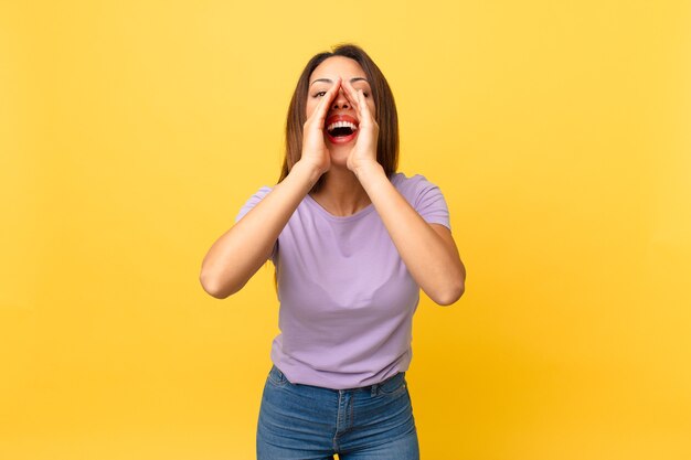 Jovem mulher hispânica se sentindo feliz, dando um grande grito com as mãos perto da boca