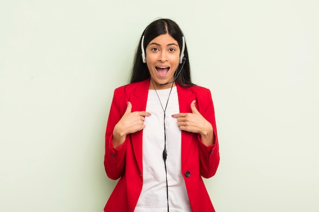 Jovem mulher hispânica se sentindo feliz e apontando para si mesmo com um animado. conceito de telemarketing