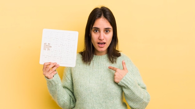 Jovem mulher hispânica se sentindo feliz e apontando para si mesmo com um conceito de quebra-cabeça animado
