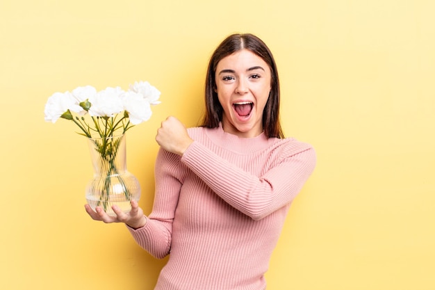 Jovem mulher hispânica se sentindo feliz e enfrentando um desafio ou comemorando. conceito de vaso de flores