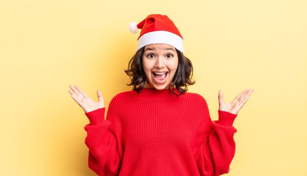 Jovem mulher hispânica se sentindo feliz e surpresa com algo inacreditável. conceito de natal