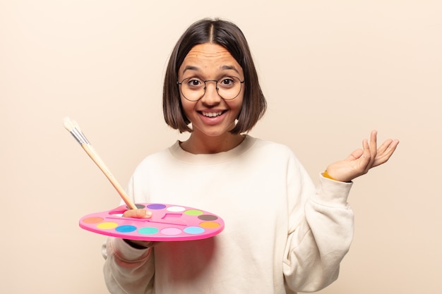 Jovem mulher hispânica se sentindo feliz, surpresa e alegre, sorrindo com atitude positiva, percebendo uma solução ou ideia