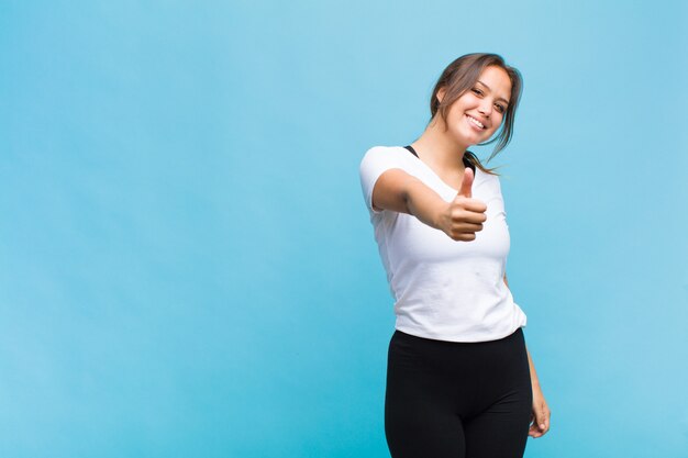 Jovem mulher hispânica se sentindo orgulhosa, despreocupada, confiante e feliz, sorrindo positivamente com o polegar para cima