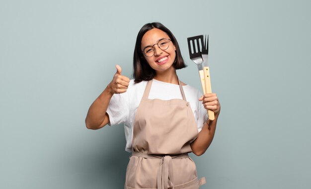 Jovem mulher hispânica se sentindo orgulhosa, despreocupada, confiante e feliz, sorrindo positivamente com o polegar para cima