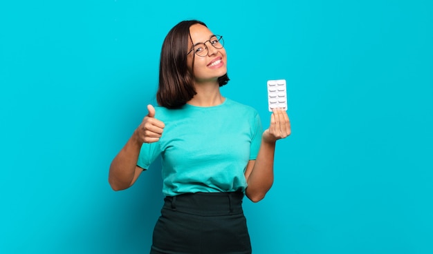 Jovem mulher hispânica se sentindo orgulhosa, despreocupada, confiante e feliz, sorrindo positivamente com o polegar para cima