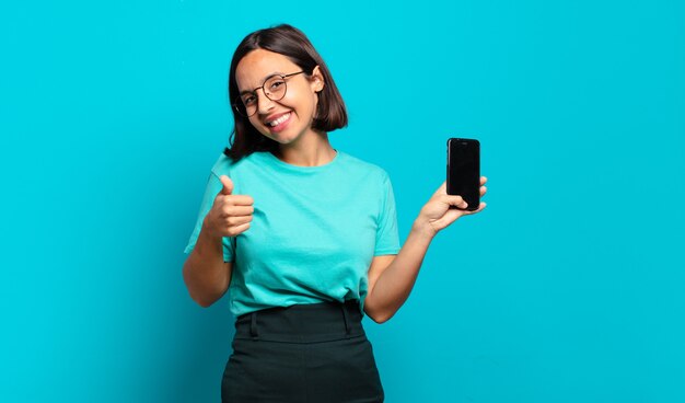 Jovem mulher hispânica se sentindo orgulhosa, despreocupada, confiante e feliz, sorrindo positivamente com o polegar para cima