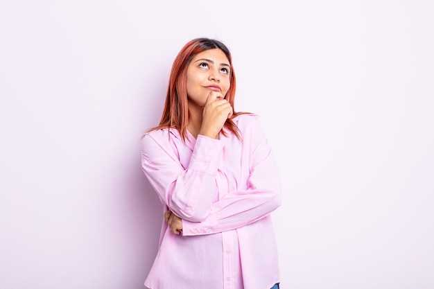 Jovem mulher hispânica se sentindo pensativa, imaginando ou imaginando ideias, sonhando acordada e olhando para cima para copiar o espaço