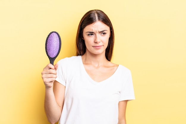 Jovem mulher hispânica se sentindo triste, chateada ou com raiva e olhando para o lado. conceito de escova de cabelo