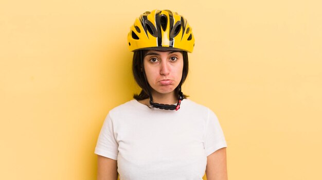 Jovem mulher hispânica se sentindo triste e chorosa com um olhar infeliz e chorando o conceito de capacete de bicicleta