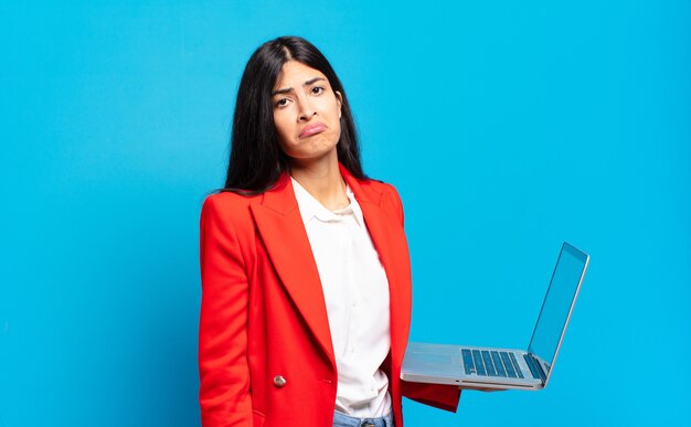 Jovem mulher hispânica se sentindo triste e resmungona com um olhar infeliz, chorando com uma atitude negativa e frustrada. conceito de laptop