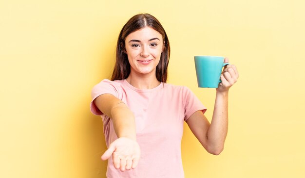 Jovem mulher hispânica, sorrindo alegremente com simpáticos e oferecendo e mostrando um conceito. conceito de xícara de café