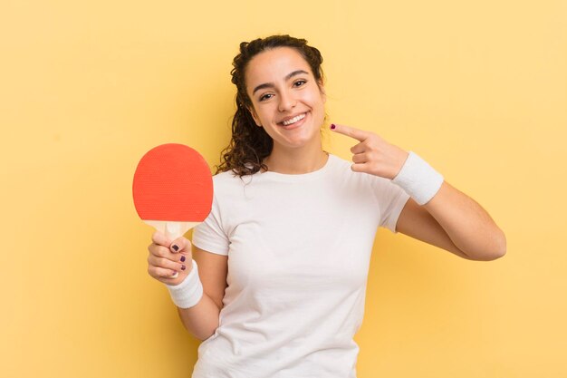 Jovem mulher hispânica sorrindo com confiança apontando para o próprio conceito de ping pong de sorriso largo