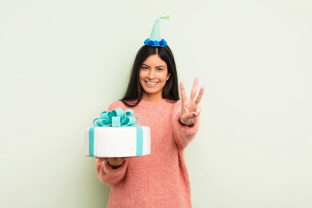 Jovem mulher hispânica sorrindo e parecendo amigável, mostrando o conceito de bolo de aniversário número três