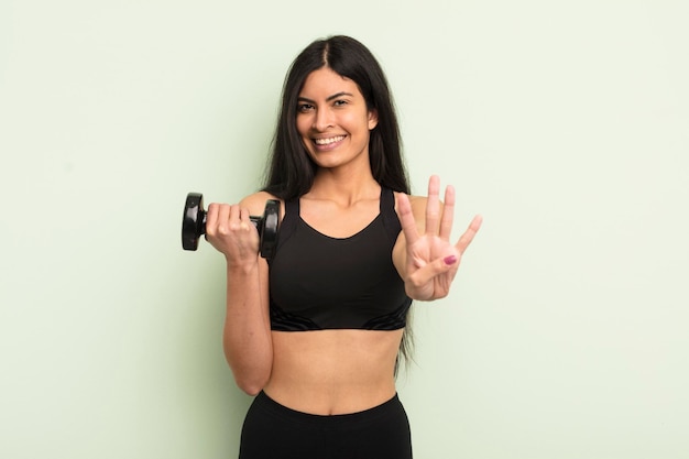 Jovem mulher hispânica sorrindo e parecendo amigável, mostrando o conceito de fitness número quatro