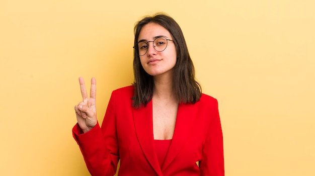 Jovem mulher hispânica sorrindo e parecendo amigável mostrando o conceito de negócio número dois