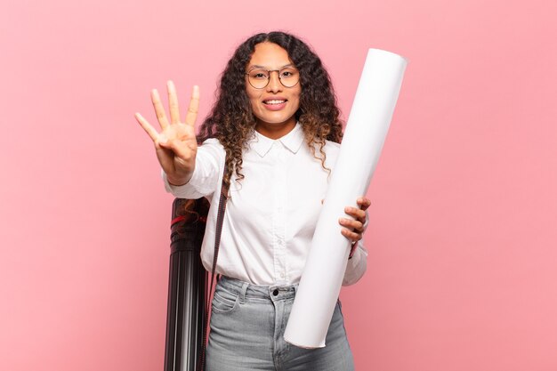 Jovem mulher hispânica sorrindo e parecendo amigável, mostrando o número quatro ou quarto com a mão para a frente, em contagem regressiva. conceito de arquiteto