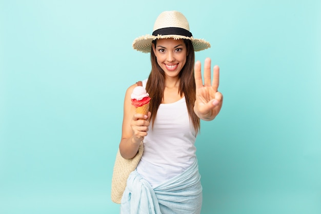 Jovem mulher hispânica sorrindo e parecendo amigável, mostrando o número três e segurando um sorvete. conceito de sumer