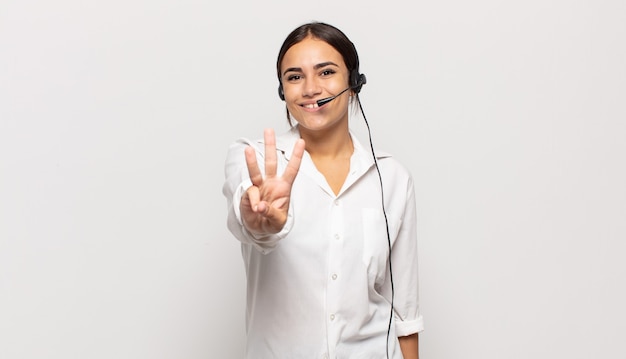 Foto jovem mulher hispânica sorrindo e parecendo amigável, mostrando o número três ou terceiro com a mão para a frente, em contagem regressiva