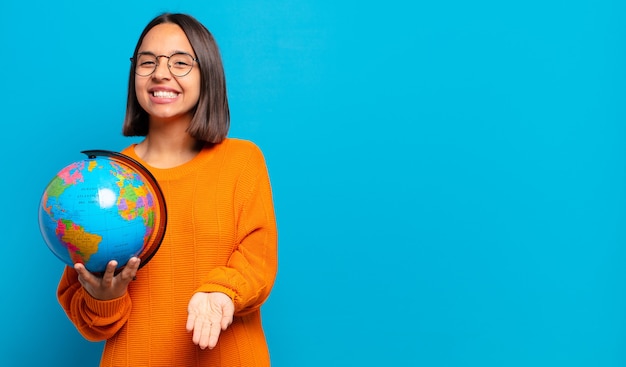 Jovem mulher hispânica sorrindo feliz com um olhar amigável, confiante e positivo, oferecendo e mostrando um objeto ou conceito