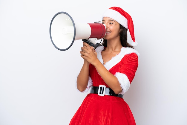 Jovem mulher hispânica vestida como mama noel isolada no fundo branco gritando através de um megafone