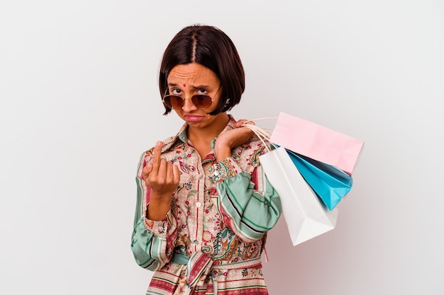 Jovem mulher indiana comprando algumas roupas isoladas no fundo branco, apontando com o dedo para você como se fosse um convite para se aproximar.