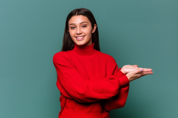 Jovem mulher indiana em azul, segurando um espaço de cópia na palma da mão.