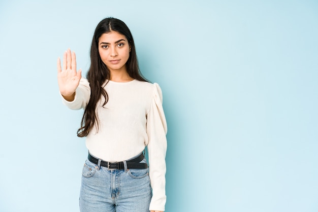 Jovem mulher indiana isolada na parede azul em pé com a mão estendida, mostrando o sinal de stop, impedindo você.