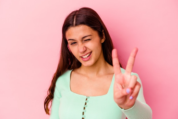 Jovem mulher indiana isolada na parede rosa, mostrando o número dois com os dedos.