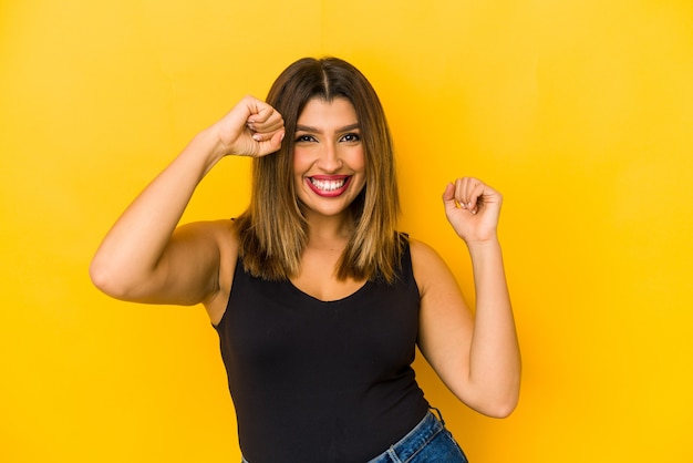 Jovem mulher indiana isolada no espaço amarelo, dançando e se divertindo.