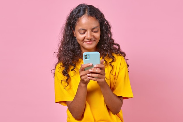 Jovem mulher indiana sorridente com os olhos fechados segura um smartphone no estúdio