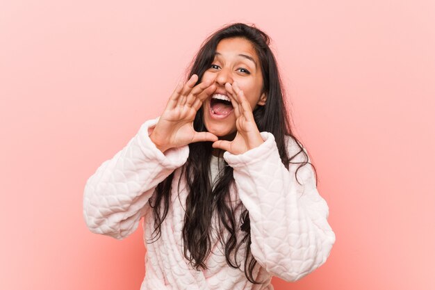 Jovem mulher indiana vestindo pijama gritando animado para a frente.