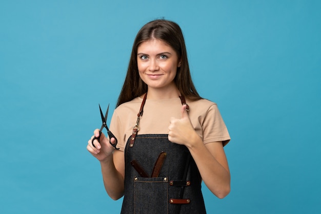 Foto jovem mulher isolada parede azul com cabeleireiro ou barbeiro vestido com o polegar para cima