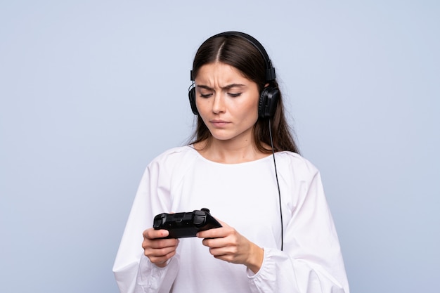 Jovem mulher isolada parede azul jogando em videogame