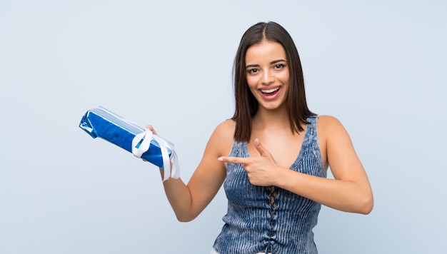 Jovem mulher isolada parede azul segurando a caixa de presente