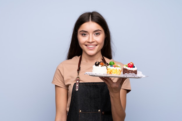 Jovem mulher isolada parede azul segurando mini bolos