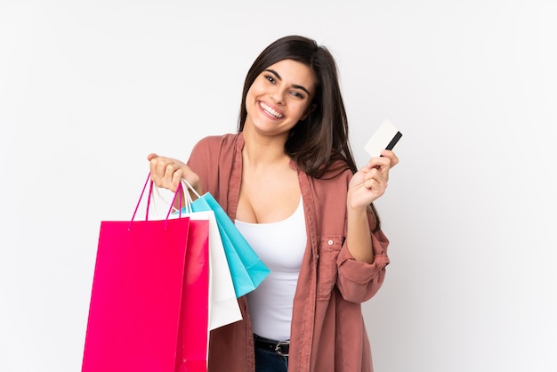 Jovem mulher isolada parede branca segurando sacolas de compras e um cartão de crédito