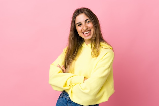 Jovem mulher isolada parede rosa com os braços cruzados e olhando para a frente