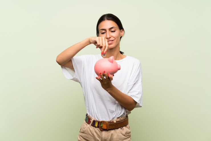 Foto jovem mulher isolada parede verde segurando um grande piggybank