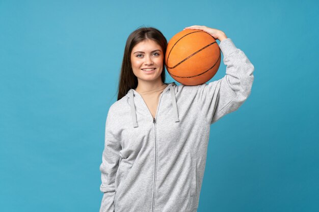 Jovem mulher isolado azul com bola de basquete