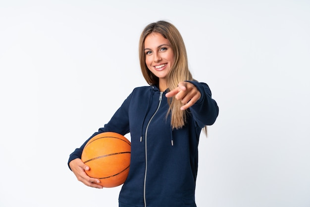 Jovem mulher jogando basquete na parede branca isolada