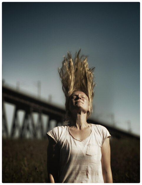 Foto jovem mulher jogando cabelos loiros longos contra o céu
