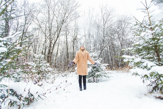 Jovem mulher jogando neve para o ar em um dia ensolarado de inverno, ela é feliz e divertida.