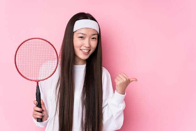 Jovem mulher jogando pontos isolados de badminton com o dedo polegar, rindo e despreocupado
