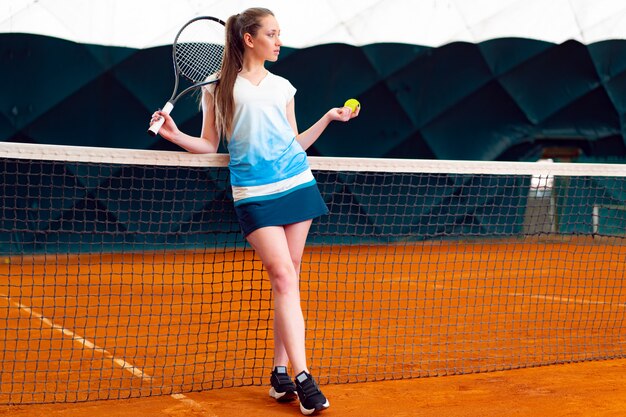 Jovem mulher jogando tênis na quadra de tênis coberta